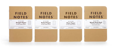 Four kraft brown 3-packs of Field Notes with white paper bands and Field Notes logo in black ink. From left to right: A 3-pack with graph paper, ruled paper, plain paper, and a mixed three-pack.