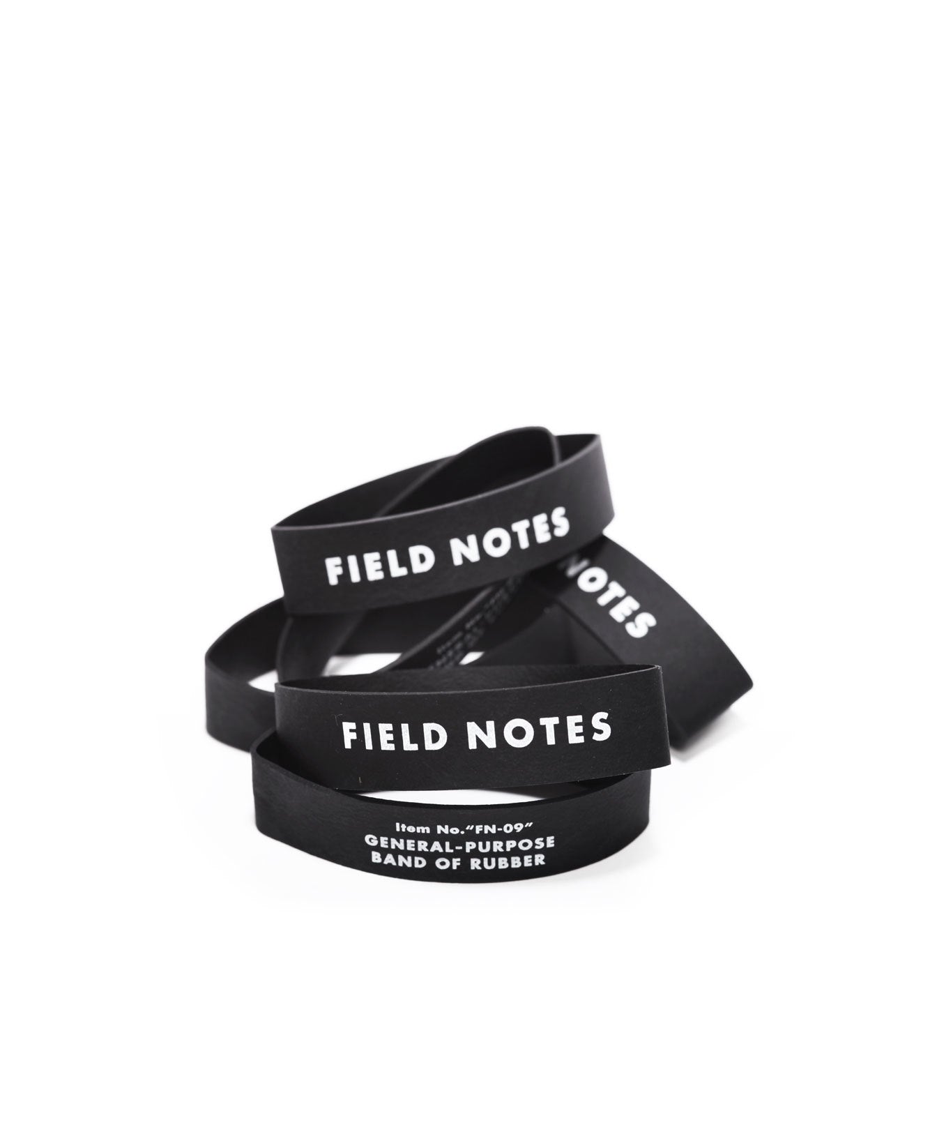 A pile of 3” by 5/8” black rubber bands with Field Notes logo in white ink.