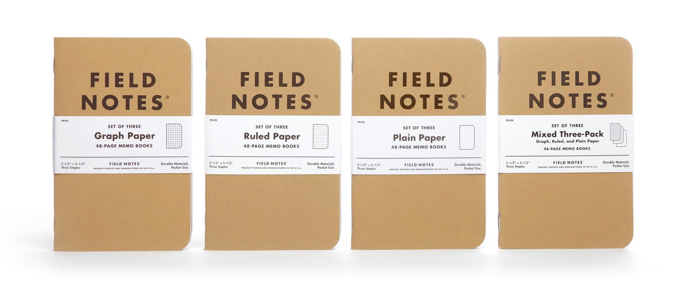 Four kraft brown 3-packs of Field Notes with white paper bands and Field Notes logo in black ink. From left to right: A 3-pack with graph paper, ruled paper, plain paper, and a mixed three-pack.